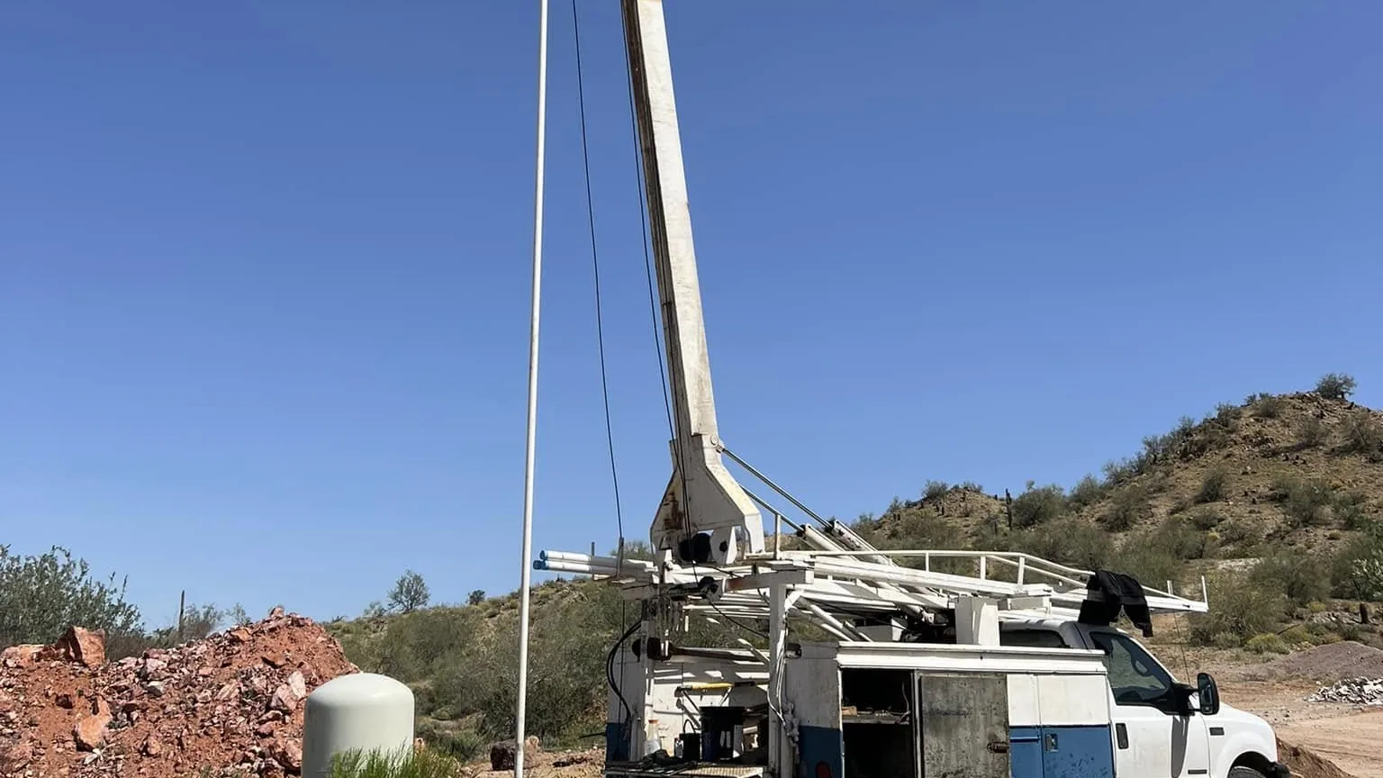 Pump hoist truck with its mast raised over a water well in Arizona ranch country