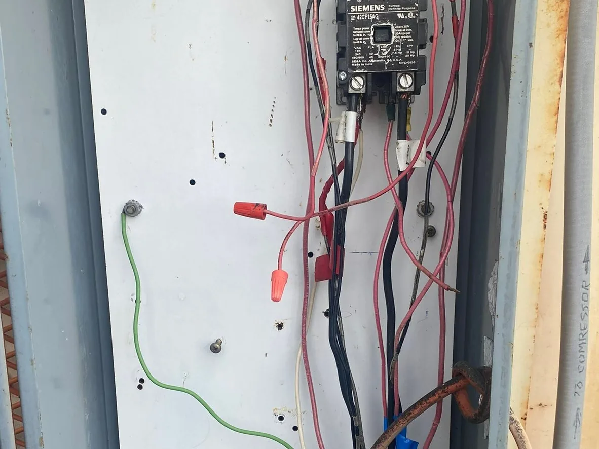 Open pump control panel wired beside a water tank