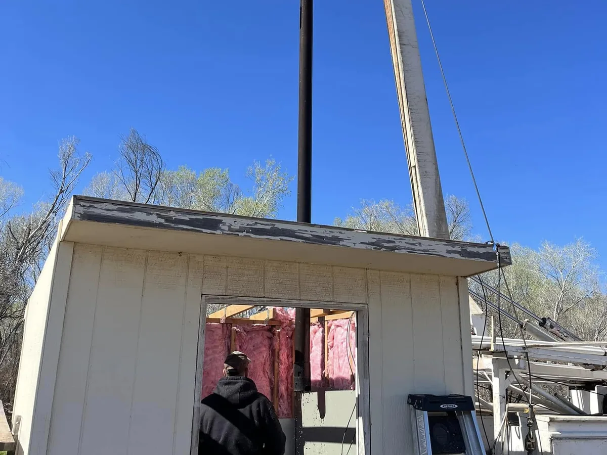 Pump hoist truck set up beside a well house during a pump service call