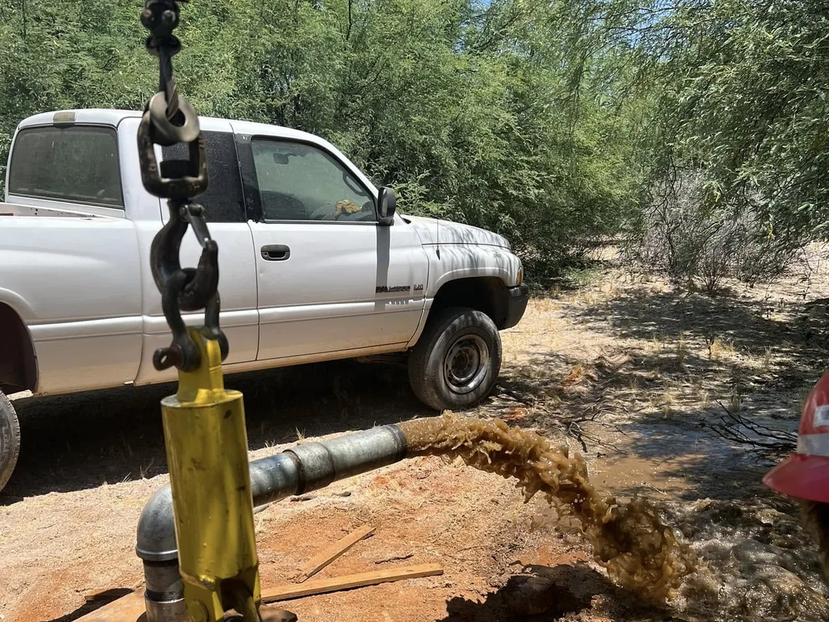 Drop pipe being pulled up out of a water well on the rig hook
