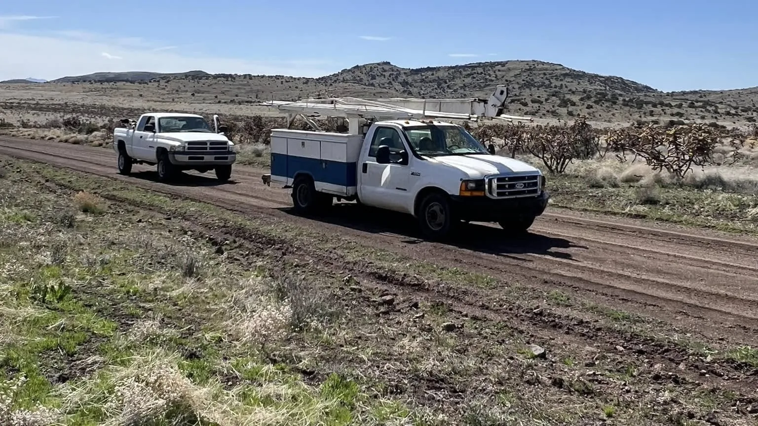 Service trucks on a ranch road heading out to a well job in Arizona