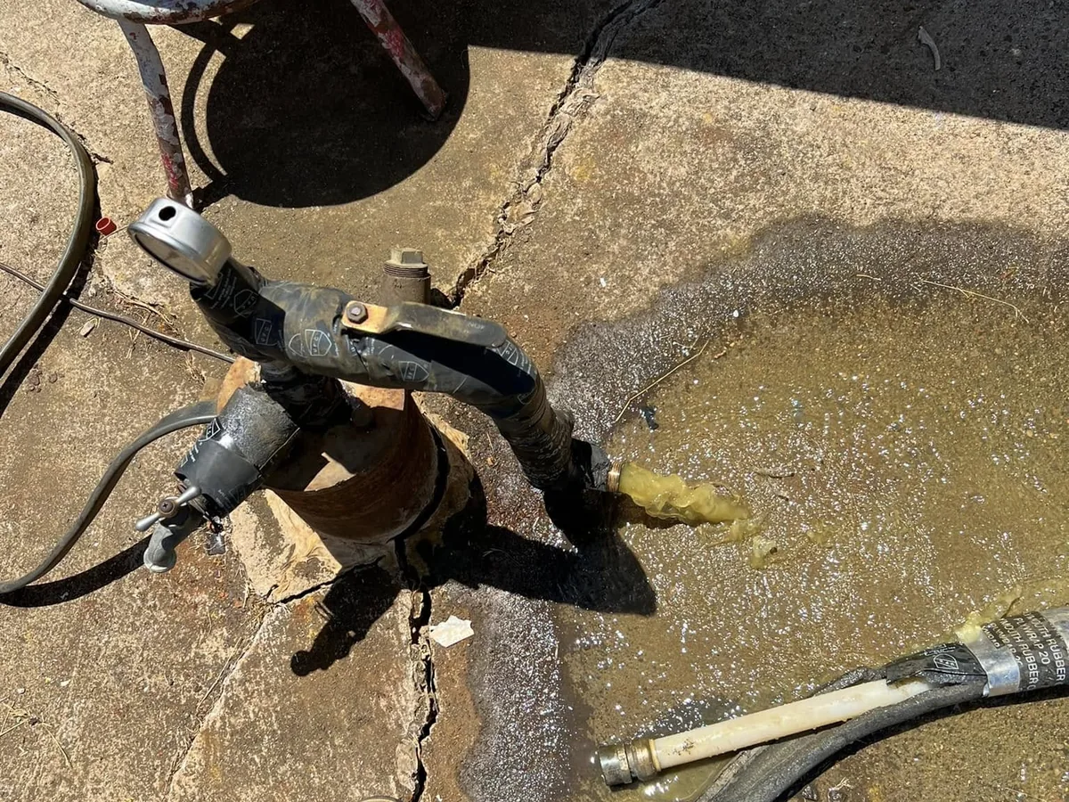 Hoist clamp set on the drop pipe at the wellhead while a pump goes down the hole