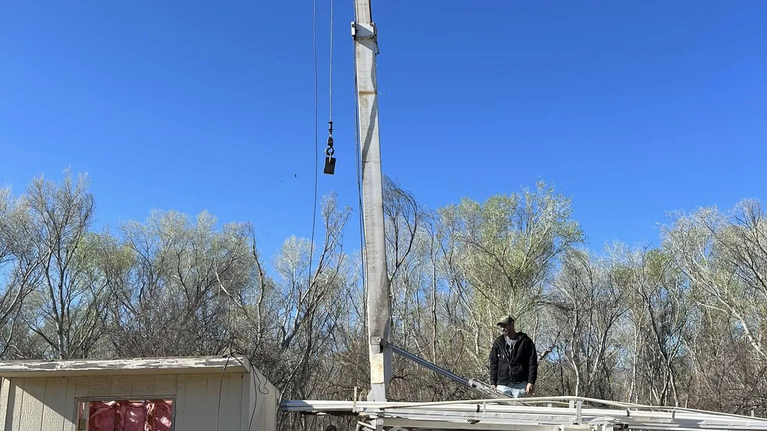 Pump hoist truck and service truck working a well beside a well house