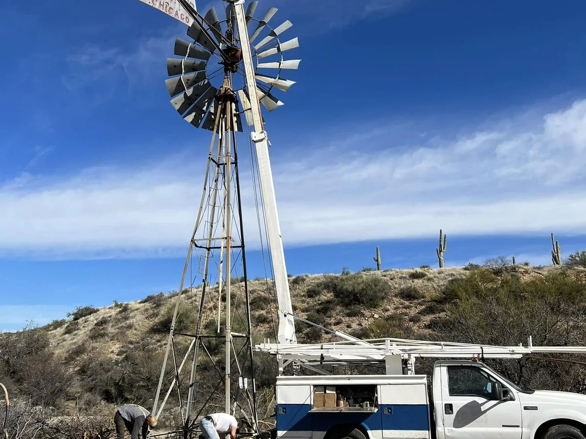 Water-pumping windmill on its tower with the service truck parked alongside